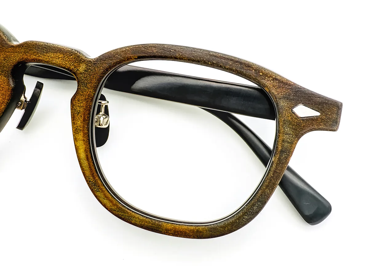 Close-up of natural horn showing brown tonal variation around the lens opening and a silver-tone endpiece inlay