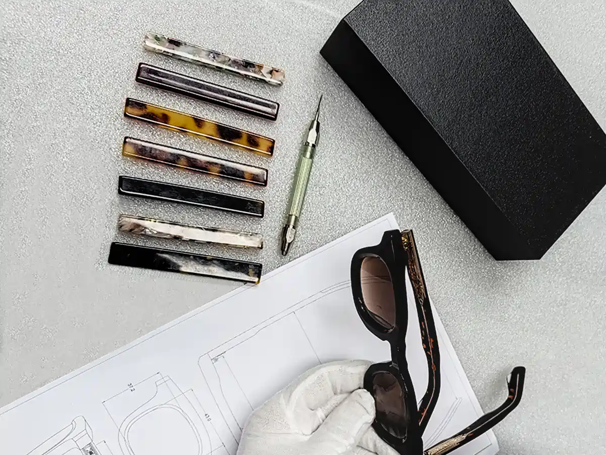 Custom eyewear sample under engineering review with technical drawing and acetate swatches