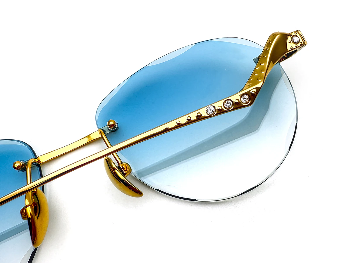 Titanium sunglasses with exposed lens mounts and decorative temple hardware